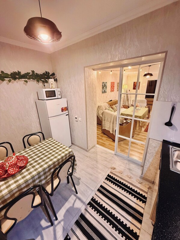 Un coin repas avec une nappe à carreaux, un four à micro-ondes et un tapis à motifs.