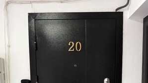 Una puerta negra con el número 20, una cerradura y un pequeño candado.