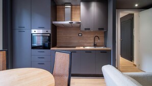 A modern kitchen with built-in appliances, a wooden countertop, and a dining area with a round table and chairs. - 2 bedroom lovely apartment in Santa Margherita (Santa Margherita)