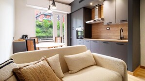 A modern living room with a sofa, a dining table, and a kitchen area with cabinets and a stove. - 2 bedroom lovely apartment in Santa Margherita (Santa Margherita)