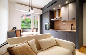 A modern living room with a sofa, a dining table, and a kitchen area with cabinets and a stove. - 2 bedroom lovely apartment in Santa Margherita (Santa Margherita)
