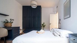 A bedroom with a bed, bedside tables, a desk, a chair, a wardrobe, and a hanging light fixture. - 2 bedroom lovely apartment in Santa Margherita (Santa Margherita)