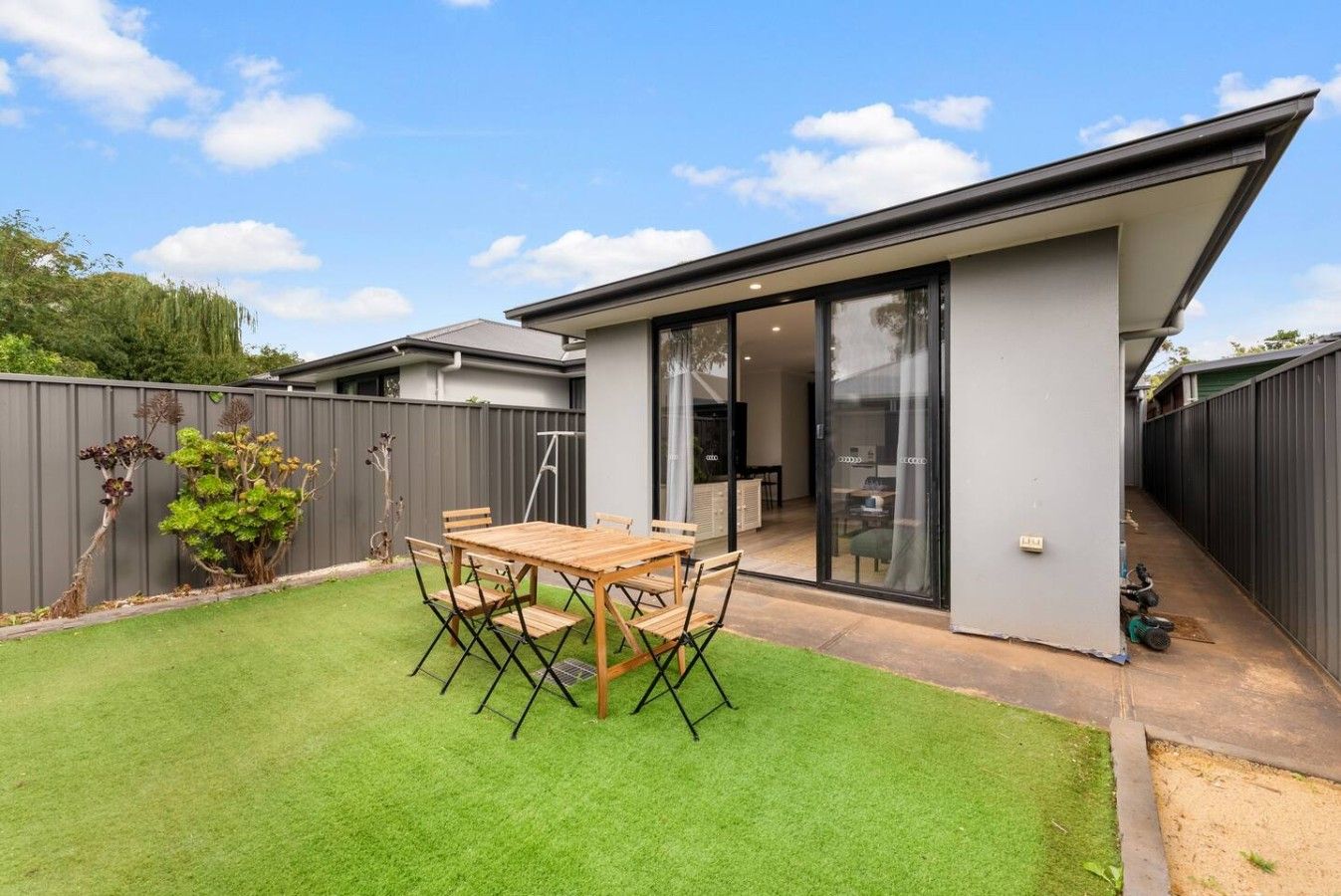 A modern house with a patio, a dining table, and a covered outdoor area.