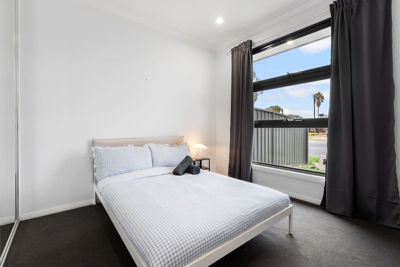 A bedroom with a bed, a nightstand, a lamp, and a window with curtains.