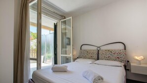 Una camera da letto con un letto, una finestra con tende e un comodino con una lampada, e vista sull'esterno.