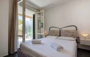 A bedroom with a bed, a window with curtains, a nightstand with a lamp, and a view of the outside. - Gorgeous apartment in Borgio Verezzi with WiFi (Borgio Verezzi)