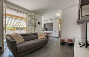 A modern living room with a sofa, ottomans, a dining area, and a kitchen in the background. - Gorgeous apartment in Borgio Verezzi with WiFi (Borgio Verezzi)