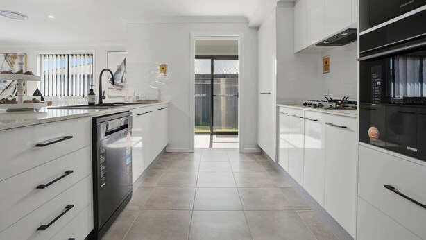 A modern kitchen with white cabinetry, a dishwasher, a stove, and a refrigerator. - Whistling Way Wonderscape - Modern 4 Bed, 2 Bath (Orange)