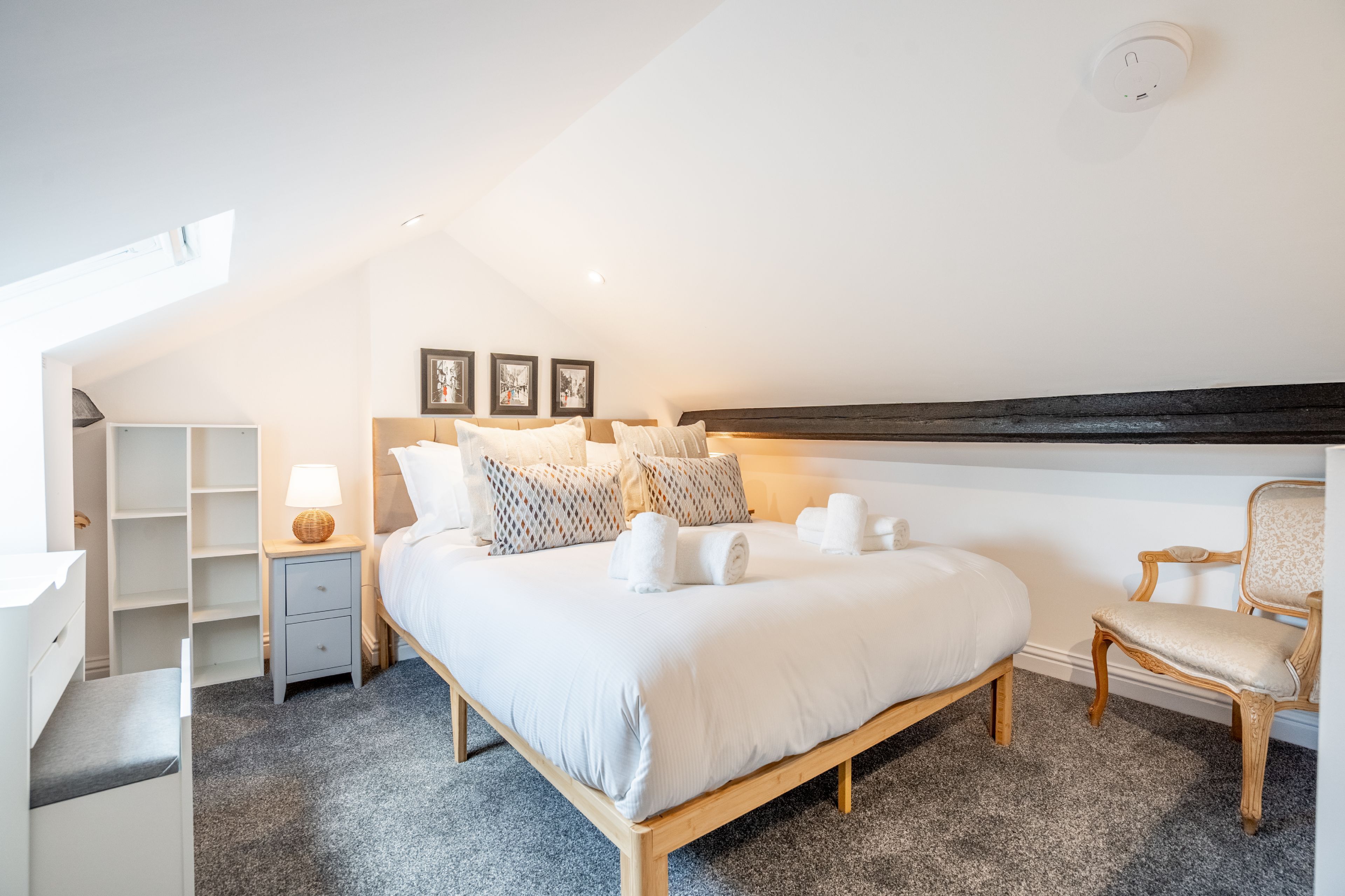 A bedroom with a bed, bedside tables, a chair, and a wardrobe.