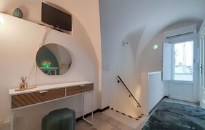 Ein modernes Zimmer mit Schreibtisch, Stuhl, Fernseher und einem großen Spiegel.