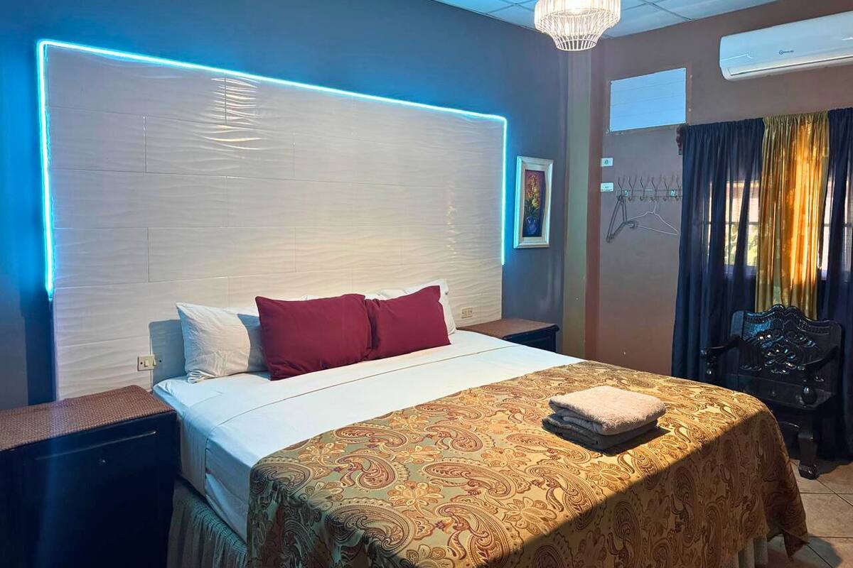 Een hotelkamer met een bed, nachtkastje, lamp en uitzicht.