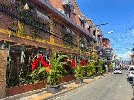 A street view with buildings, cars, and potted plants along the sidewalk.. Hotel Maya Copan Centro