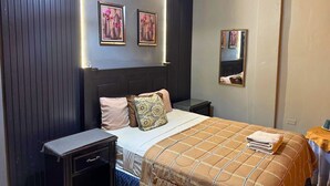 Une chambre d’hôtel comprenant un lit, des tables de chevet, une commode, un miroir et des œuvres d’art accrochées au mur.