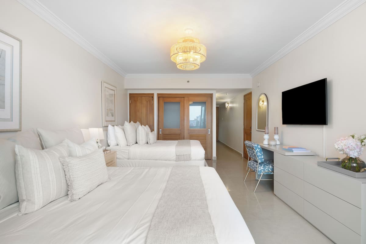 Una habitación de hotel con una cama grande, un escritorio, una silla, un televisor y un armario.