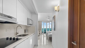 A modern kitchen with a black countertop, stainless steel sink, and white cabinets.