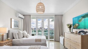 A hotel room with two beds, a large window with a view of a cityscape, a television, and a wooden dresser.