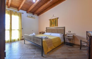 Ein Zimmer mit einem Bett, einer Wandteppich, einer Holzbalkendecke und einem Fenster mit Vorhängen.