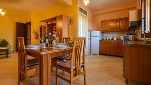 Un comedor con sillas de madera, una mesa dispuesta para cuatro personas y un jarrón con flores.