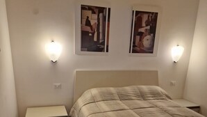 Een slaapkamer met een bed, nachtkastjes en wandlampen.