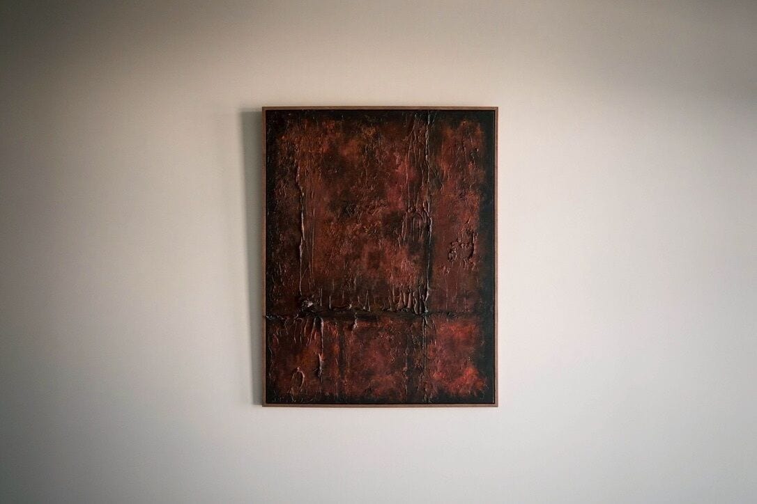 A framed abstract painting on a plain wall.