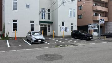Un parcheggio con due auto, un edificio con molte finestre e un segnale che indica il costo del parcheggio.