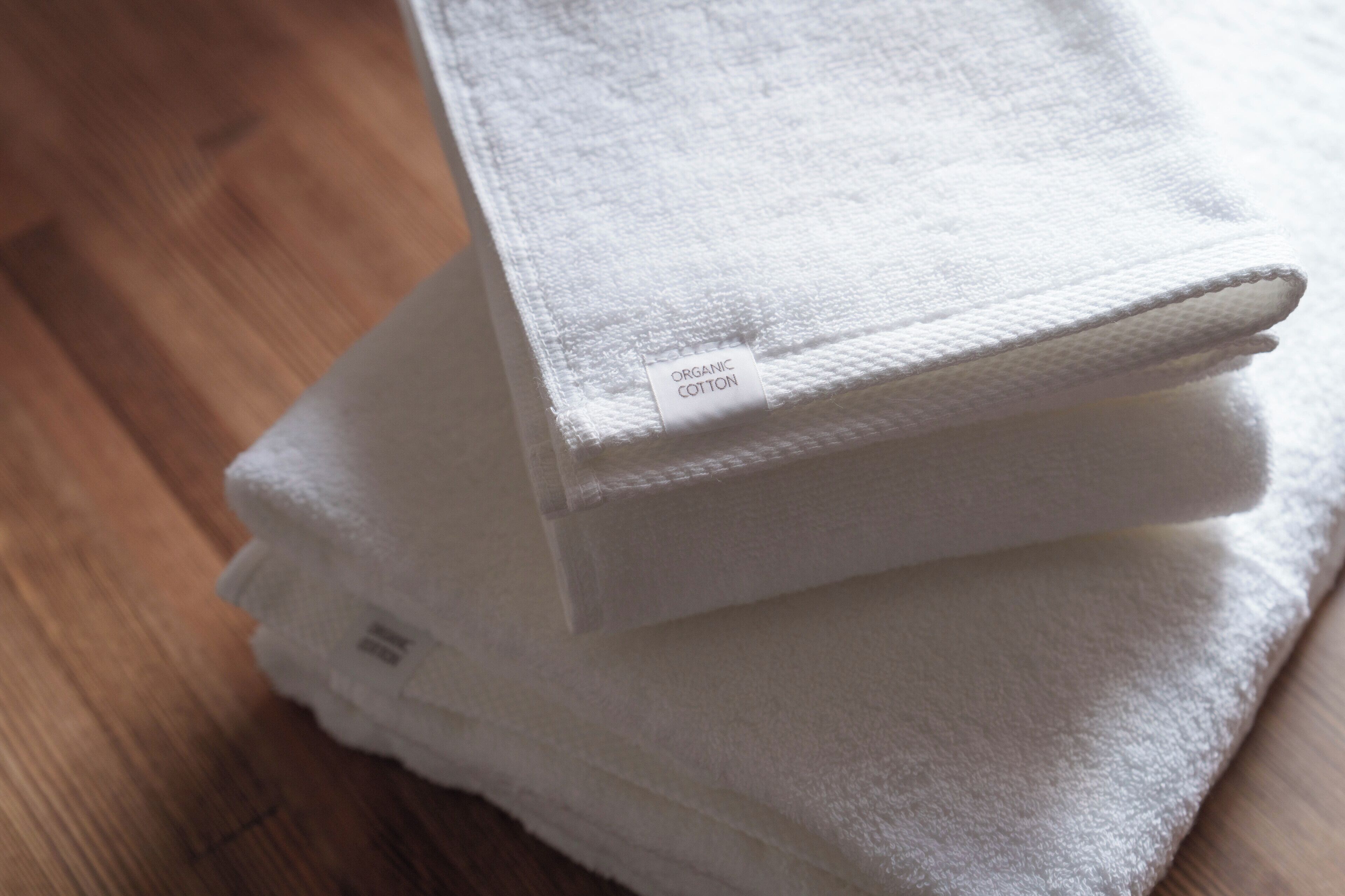 A stack of white towels with a label indicating they are organic cotton.