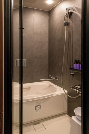 A modern bathroom with a glass-enclosed shower, a white bathtub, and a toilet.
