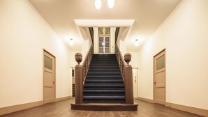 A grand staircase with a chandelier, a door at the top, and a window with a decorative grille. - T9 HAKODATE (Hakodate)
