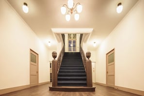 A grand staircase with a chandelier, a door at the top, and a window with a decorative grille. - T9 HAKODATE (Hakodate)