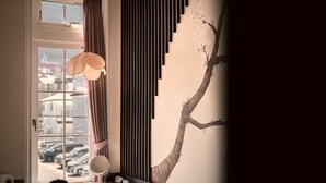 A room with a window, a hanging lamp, a wall-mounted mirror, and a tree mural. - T9 HAKODATE (Hakodate)