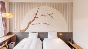 A hotel room with two beds, a wall-mounted artwork of a tree, a desk, and a nightstand. - T9 HAKODATE (Hakodate)