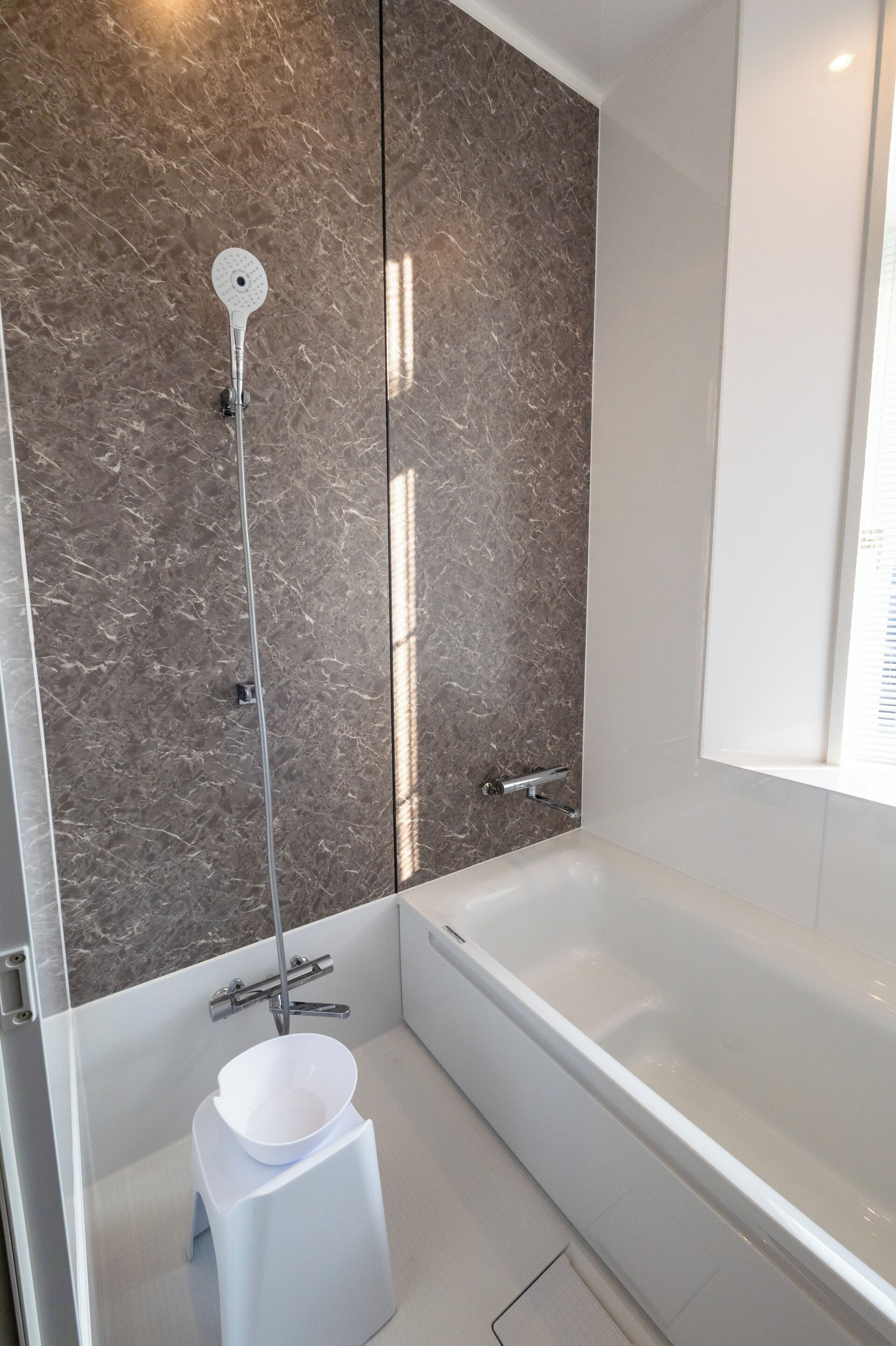 Une salle de bain moderne avec une baignoire, une douche équipée d’un pommeau de douche à main et un lavabo blanc.