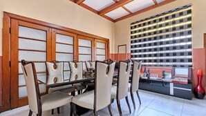 A dining area with a glass table, wooden chairs, a tiled floor, and a wall with a checkered pattern. - Room-45 On Westmoreland Luxury Guest Hou (Johannesburg)