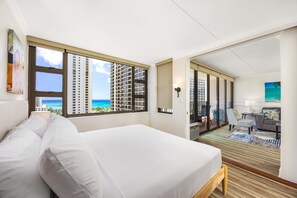 Une chambre d’hôtel avec un grand lit, un bureau, une chaise et une vue sur l’océan.