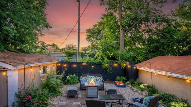 Ein Garten mit Feuerstelle, Sitzgelegenheiten im Freien und Lichterketten.