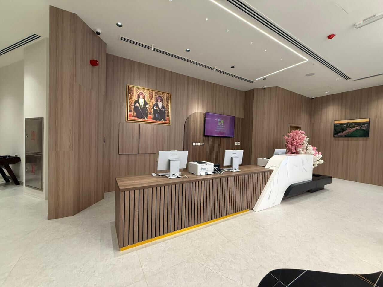 A reception desk with computers, a television, and a floral arrangement.