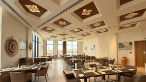 Un comedor amplio con varias mesas y sillas, ventanas grandes y un diseño moderno de techo.