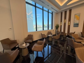A hotel lobby with a modern design, featuring a large window with a city view, multiple seating areas, and a polished floor. - Swiss-Belhotel Nizwa (Nizwa)