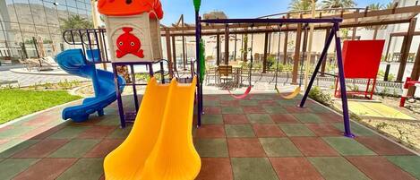 A playground with slides and swings under a canopy.