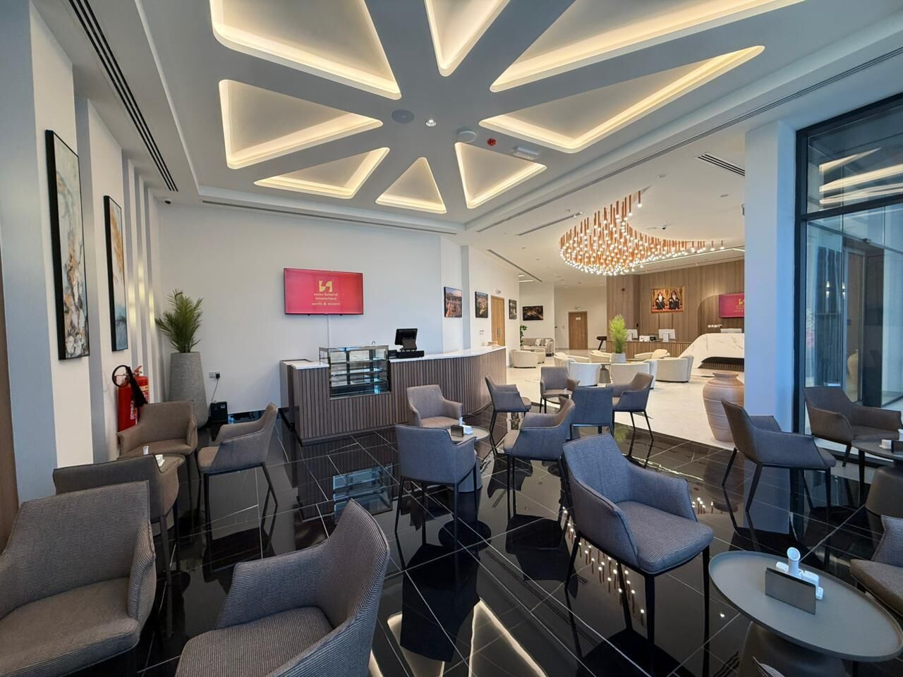 Eine moderne Hotellobby mit Sitzbereichen, einem Empfangstresen und einer Kandelaber.