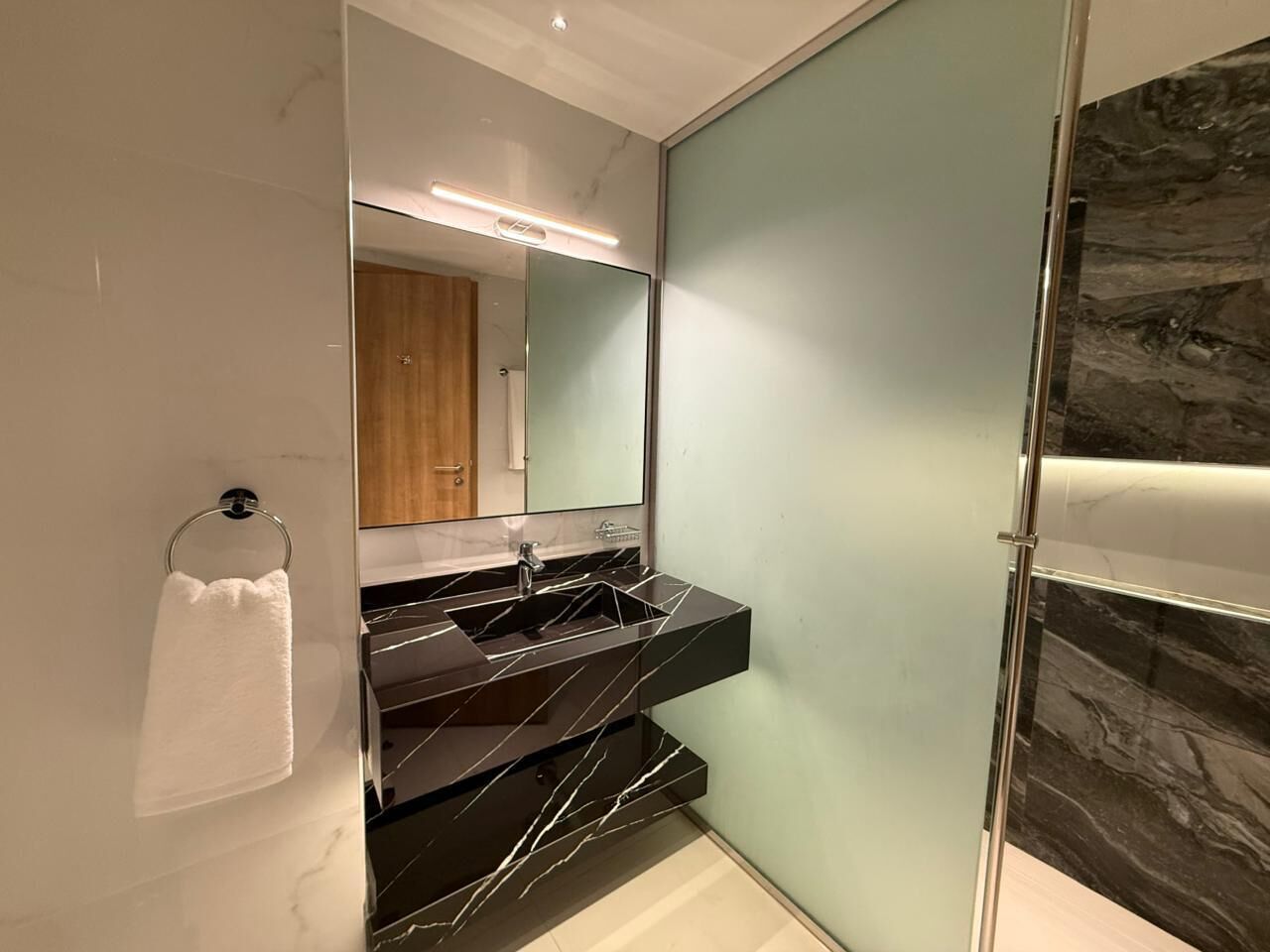 Un baño moderno con cabina de ducha de vidrio, tocador con lavabo y espejo.
