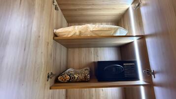 Un mueble de madera con un almohadón blanco, un cojín estampado y un dispositivo electrónico negro.