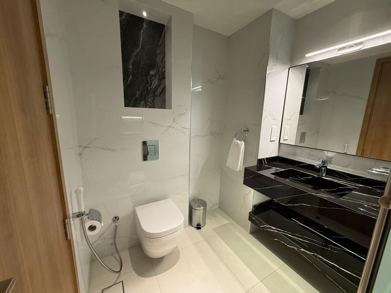 A modern bathroom with a toilet, bidet, and a black marble sink.