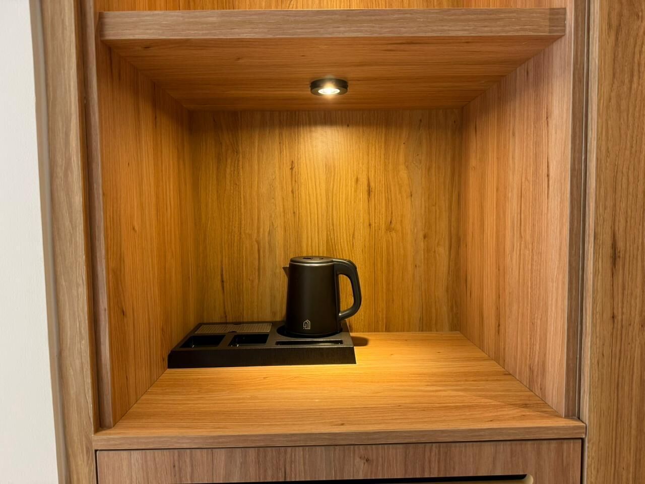 A wooden cabinet with a black coffee maker on top.