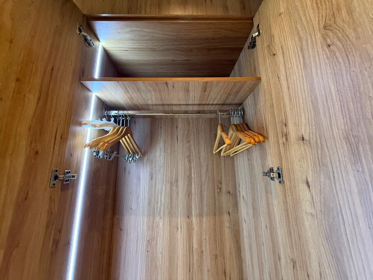 A wooden interior with a built-in shelf and hooks for hanging items.