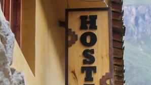 Un letrero de madera que dice 'HOSTAL KILLARI', indicando una residencia para huéspedes.