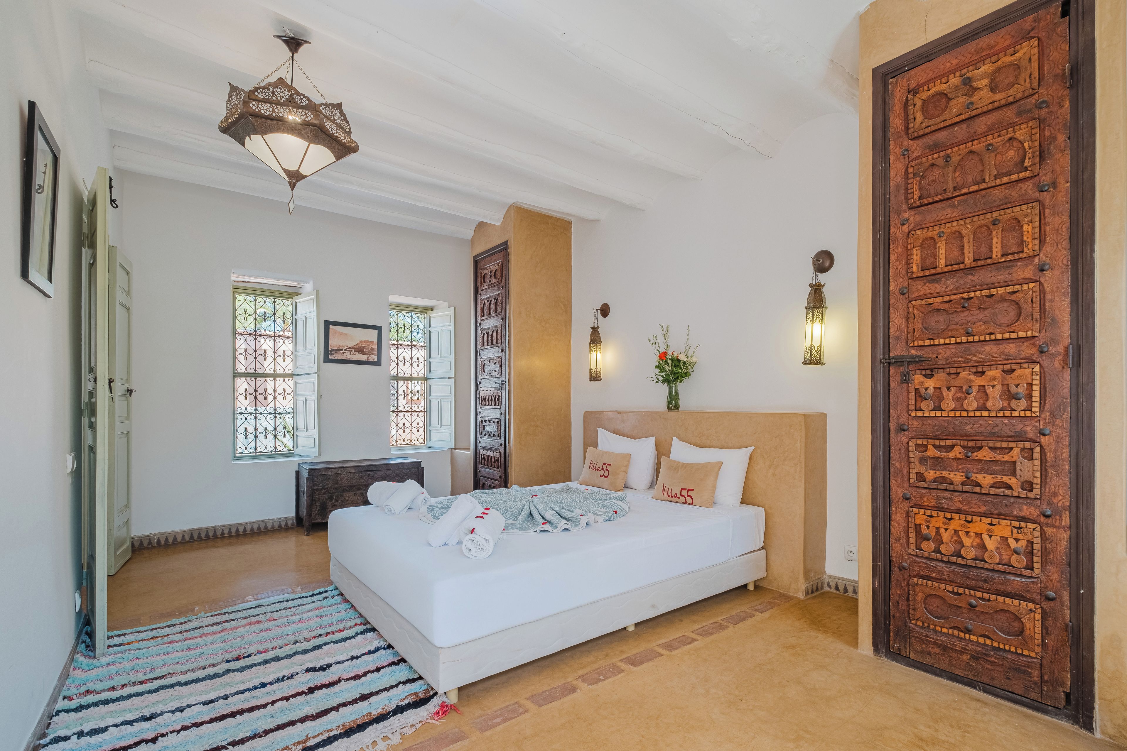 Une chambre spacieuse avec un grand lit, une porte en bois et un luminaire décoratif au plafond.