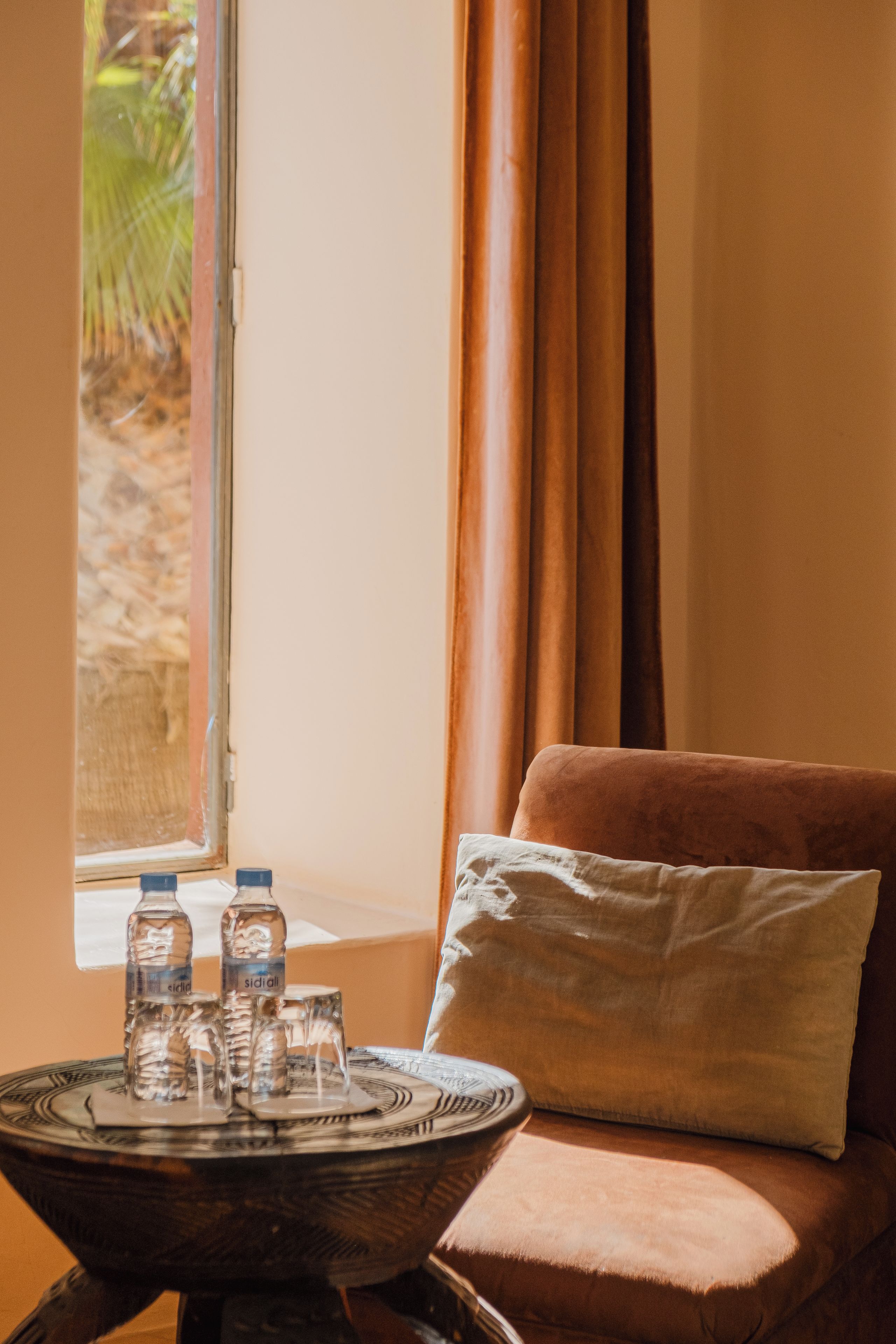 Ein Zimmer mit Fenster, einer Couch und einem Tisch mit Wasserflaschen und Gläsern.