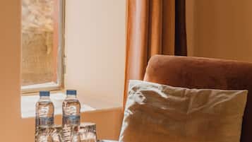Ein Zimmer mit Fenster, einer Couch und einem Tisch mit Wasserflaschen und Gläsern.