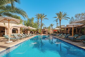 A swimming pool with lounge chairs and umbrellas, surrounded by palm trees. - Hotel Dar 55 Berbere House & Spa (Marrakech)